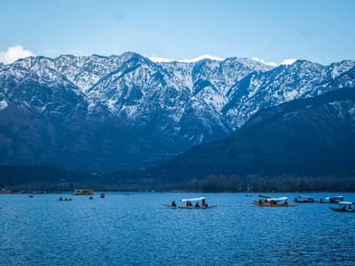 Shikara boats moored on Dal Lake with the Zabarwan mountain range rising behind them